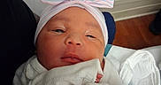 Aaliyah is registered to the contest to win money with this photo: newborn, baby, infant, child, portrait, face, eyes, nose, mouth, headwear, bow, hat, striped, pink, blue, blanket, white_clothing, swaddled, indoors, close_up