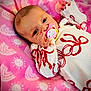 Autumn is registered to the contest to win money with this photo: baby, pacifier, blanket, pink, white_clothing, red_bows, infant, face, hand, cute, lying_down, pattern, soft_texture, closeup, newborn, child, sleepwear, comfort, portrait, indoors