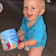 Carter is registered to the contest to win money with this photo: toddler, child, blue_shirt, kneeling, carpet, snack, cheez_it, can, crumbs, happy, indoor, smile, face, food, playful, person, floor, casual, cute, messy