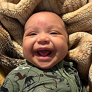 Kenneth joined the competition — help win amazing prizes! baby, smiling, face, infant, blanket, cozy, clothing, green_outfit, animal_print, fleece, soft_texture, portrait, happy, cute, child, indoors, closeup, warm, comfortable, expression