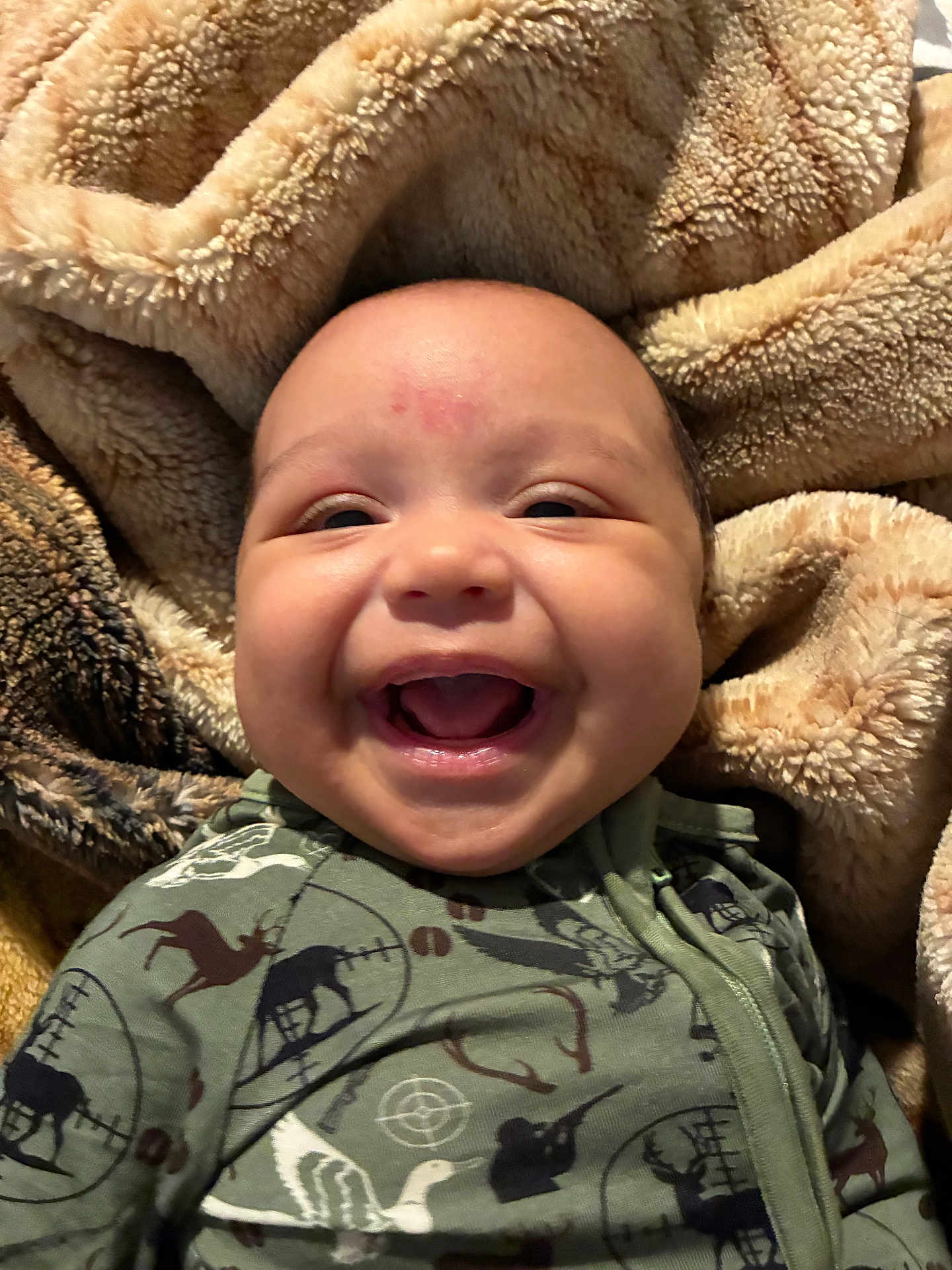 Kenneth joined the competition — help win amazing prizes! baby, smiling, face, infant, blanket, cozy, clothing, green_outfit, animal_print, fleece, soft_texture, portrait, happy, cute, child, indoors, closeup, warm, comfortable, expression