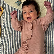 Sam Marie joined the competition — help win amazing prizes! baby, infant, pink_onesie, ruffles, smiling, happy, raised_fists, lying_down, striped_blanket, pacifier, clothing, face, person, cute, child, indoors, soft_texture, baby_accessory, closeup, portrait