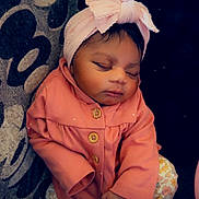 Na'Asia joined the competition — help win amazing prizes! baby, infant, sleeping, pink_jacket, headband, bow, couch, cushion, patterned_fabric, floral_pants, white_socks, peaceful, indoors, child, adorable, cute, resting, portrait, cozy, small_heart