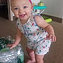 baby, barefoot, carpet, child, cute, floral_outfit, furniture, happy, headband, home, indoor, packaging, person, pink, playful, smiling, standing, toddler, toy, water_bottles