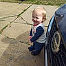 Joshua joined the competition — help win amazing prizes! toddler, child, smiling, outdoor, daylight, car, concrete, driveway, grass, car_seat, happy, blond_hair, casual_clothing, long_sleeves, footwear, side_view, shadow, residential_area, curb, sunny