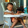 child, clothing, curtains, door, eating, face, fan, floor, food, furniture, hands, high_chair, indoor, kitchen, messy, sippy_cup, spaghetti, tile_floor, toddler, window