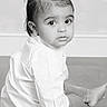 toddler, child, sitting, floor, white_shirt, pants, portrait, black_and_white, curious, wide_eyes, indoor, flooring, baby, young_child, looking_back, studio_photo, monochrome, short_hair, cute, innocent