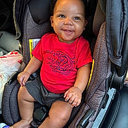Tymir joined the competition — help win amazing prizes! baby, child, car_seat, red_tshirt, smiling, happy, indoor, seatbelt, shorts, foot, hand, bottle, car_interior, person, infant, cute, sitting, clothing, face, expression