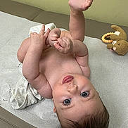 Cecilia joined the competition — help win amazing prizes! baby, infant, skin, face, eyes, tongue, hands, feet, toy, bunny, medical_table, paper_sheet, curly_hair, playful, cute, child, indoor, expression, person, lying_down