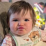baby, child, infant, portrait, face, pouting, serious_expression, brown_hair, blue_eyes, bib, bear_design, striped_clothing, seated, indoor, home, high_chair, toy, blurred_background, close_up, photography