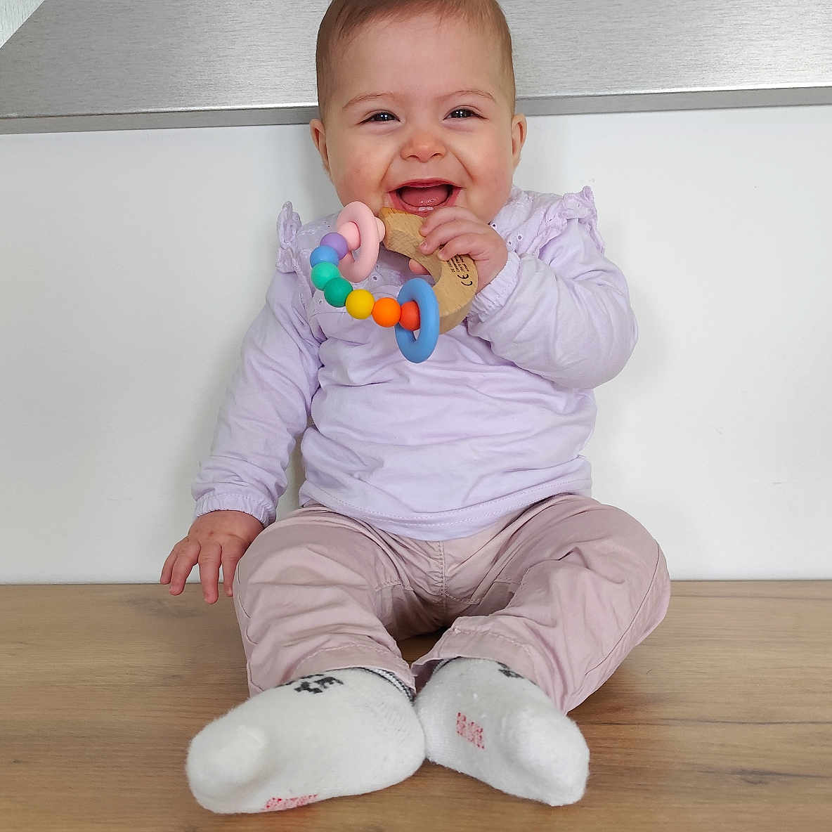 Trecy participe au concours pour gagner de l'argent avec cette photo : baby, bodypart, clothing, face, finger, footwear, hand, happy, hardwood, head, hosiery, pants, person, photography, portrait, shoe, sitting, smile, sock, wood