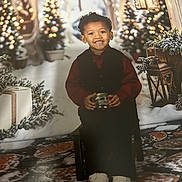 Cason joined the competition — help win amazing prizes! child, smiling, festive_clothing, chair, lantern, christmas_tree, lights, snow, gift, holiday, winter_scene, decor, indoor, happy, person, portrait, shoes, curly_hair, background, seasonal