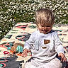 Maylo a rejoint le concours — aidez-le/la à gagner de superbes lots ! baby, blond_hair, casual_clothing, child, cute, daisy_flowers, daylight, grass, happy, nature, outdoor, play_mat, playtime, portrait, sitting, smiling, sunlight, toddler, toy, young_child