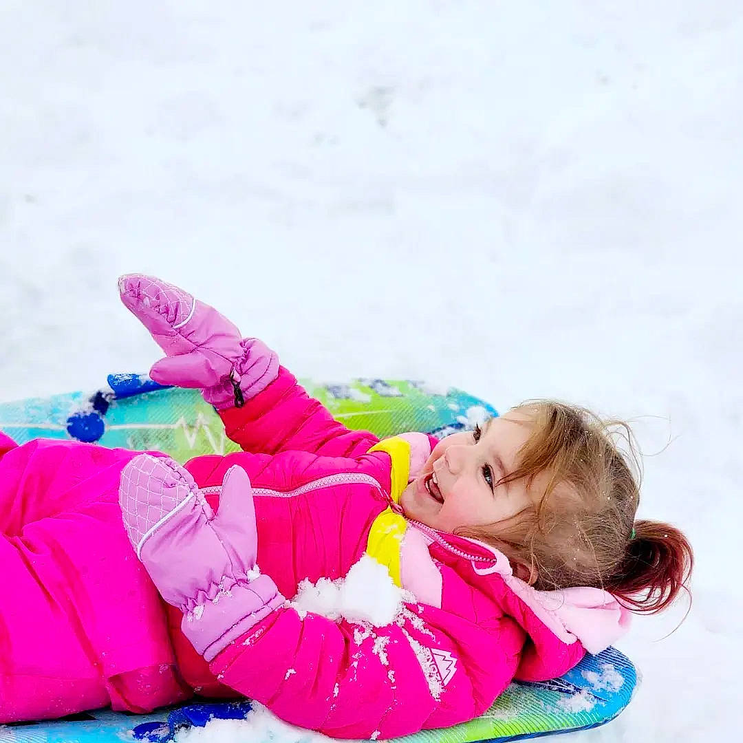 Gunner is registered to the contest to win money with this photo: baby_toddler_clothing, beanie, child, comfort, freezing, fun, happy, leisure, magenta, people_in_nature, person, pink, play, playing_in_the_snow, playing_with_kids, recreation, sitting, snow, toddler, travel