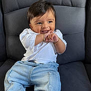 Viransh Patel is registered to the contest to win money with this photo: baby, child, smiling, happy, sitting, denim_jeans, white_shirt, bracelets, cushioned_chair, indoor, cute, playful, portrait, young_child, human, casual_clothing, black_hair, cheerful, closeup, infant