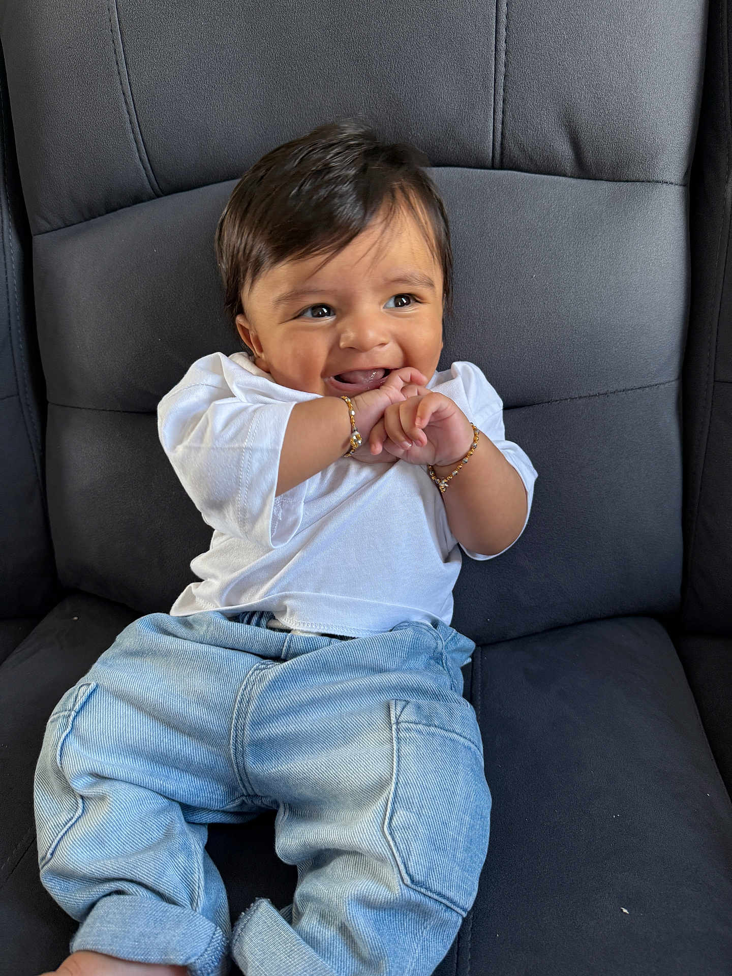 Viransh Patel is registered to the contest to win money with this photo: baby, child, smiling, happy, sitting, denim_jeans, white_shirt, bracelets, cushioned_chair, indoor, cute, playful, portrait, young_child, human, casual_clothing, black_hair, cheerful, closeup, infant