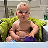 Cassius is registered to the contest to win money with this photo: baby, child, sink, water, towel, purple_cup, kitchen, window, tap, curly_hair, playful, indoors, bath_time, expression, skin, person, young, cute, sitting, clean