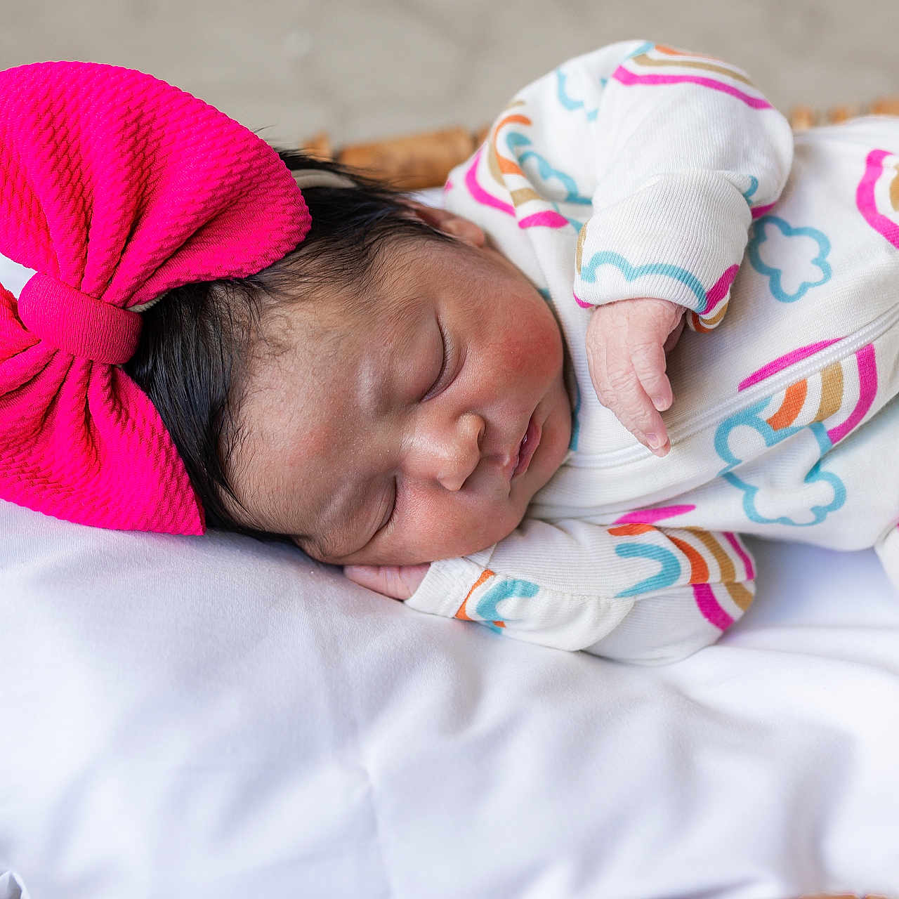 Naomi joined the competition — help win amazing prizes! newborn, baby, sleeping, pink_bow, onesie, rainbow_pattern, cloud_pattern, pillow, basket, infant, cute, resting, soft, cozy, indoor, closeup, portrait, child, peaceful, adorable