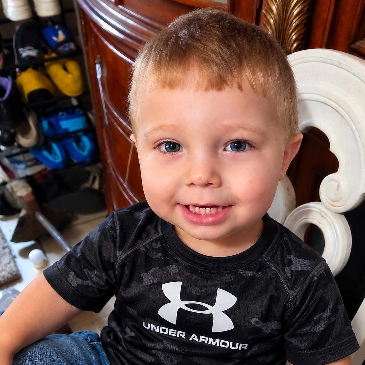 Braxton joined the competition — help win amazing prizes! child, toddler, boy, portrait, smiling, happy, indoors, seated, chair, ornate_furniture, black_shirt, sportswear, under_armour, short_hair, blue_eyes, teeth, shoe_collection, wooden_furniture, home, close_up