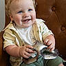 toddler, child, smiling, blue_eyes, curly_hair, shirt, shorts, mask, chair, leather, indoor, happy, cute, portrait, seated, hands, clothing, baby, person, young