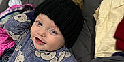 Bentley is registered to the contest to win money with this photo: baby, child, smiling, hat, knit_hat, onesie, koala_pattern, clothing, bed, blanket, fabric, person, cute, indoor, playful, sleepwear, face, portrait, headwear, toddler