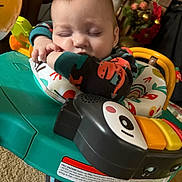 Bentley is registered to the contest to win money with this photo: baby, sleeping, infant, pajamas, dinosaur, baby_walker, toy, indoor, carpet, colorful, child, face, furniture, cozy, cute, peaceful, resting, young, person, home