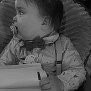 Tyméo participe au concours pour gagner de l'argent avec cette photo : baby, child, pacifier, bow_tie, suspenders, shirt, hand, book, indoor, chair, blanket, face, profile, infant, cute, portrait, seated, clothing, young, cozy