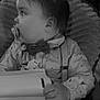 baby, child, pacifier, bow_tie, suspenders, shirt, hand, book, indoor, chair, blanket, face, profile, infant, cute, portrait, seated, clothing, young, cozy