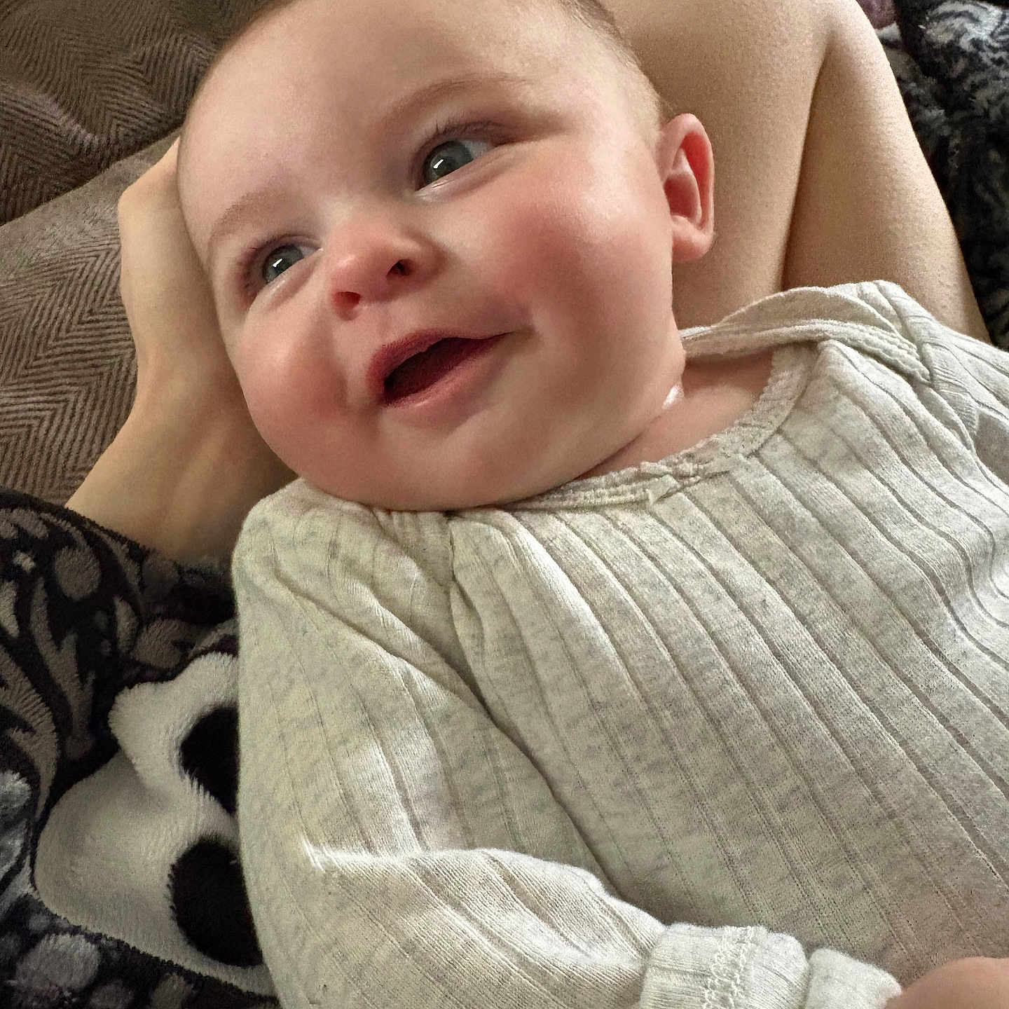 Kira is registered to the contest to win money with this photo: baby, blanket, clothing, comfort, cozy, cute, expression, eyes, fabric, face, hand, head, indoors, infant, person, portrait, sitting, skin, smiling, textile