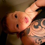 Maclovio is registered to the contest to win money with this photo: adult, arm, baby, blanket, child, close_up, cuddling, eyes, face, family, holding, indoor, infant, photography, pink_lips, portrait, shoulder, smiling, tattoo, warm_lighting