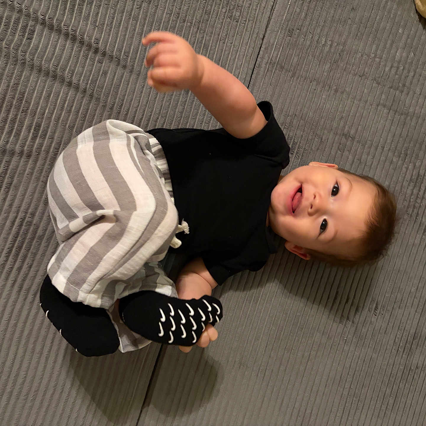 Maclovio joined the competition — help win amazing prizes! baby, black_shirt, child, face, floor, hand, happy, home, indoor, infant, lying_down, photography, playful, polka_dot, portrait, raised_hand, rug, smiling, socks, striped_pants
