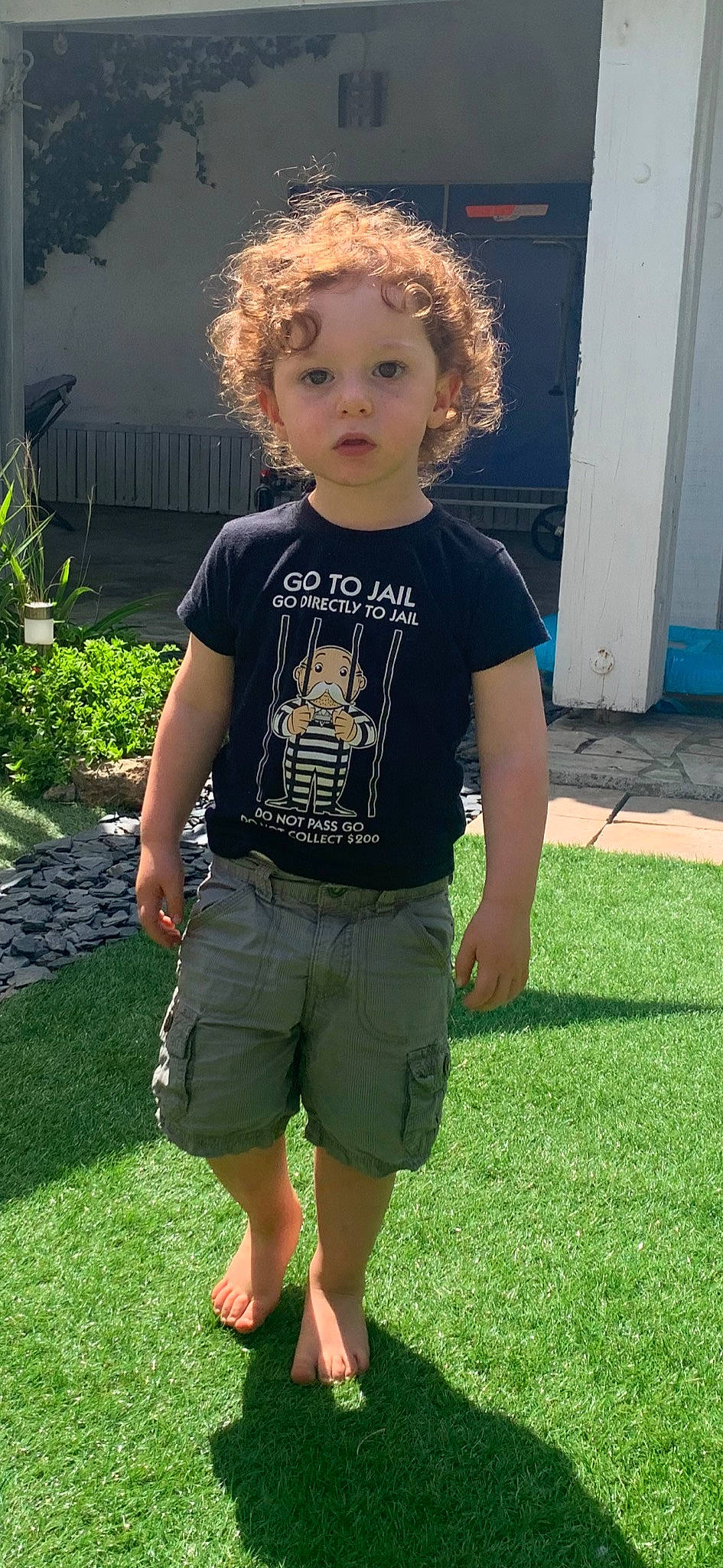 Johann participe au concours pour gagner de l'argent avec cette photo : baby_toddler_clothing, blond, door, electric_blue, eye, face, grass, green, hair, happy, head, joint, lawn, person, plant, shorts, sleeve, t_shirt, thigh, toddler