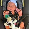 baby, infant, car_seat, orange_clothing, headband, white_flower, pacifier, plush_toy, cow_toy, feet, straps, safety, child, cute, newborn, seatbelt, indoor, person, portrait, relaxing