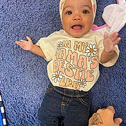 Akira is registered to the contest to win money with this photo: baby, child, tshirt, headwrap, carpet, hand, bracelet, tattoo, smile, clothing, denim, jeans, socks, person, infant, cute, playful, happy, indoor, reaching