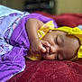 Akira is registered to the contest to win money with this photo: baby, sleeping, blanket, purple, yellow_headband, red_bedspread, infant, peaceful, closeup, face, hand, soft_texture, cozy, resting, indoors, cute, child, portrait, headwear, nap