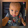 toddler, child, baby, car_seat, seatbelt, mickey_mouse, shirt, tongue, face, expression, cute, curious, hand, straps, sitting, indoor, young_child, person, portrait, playful