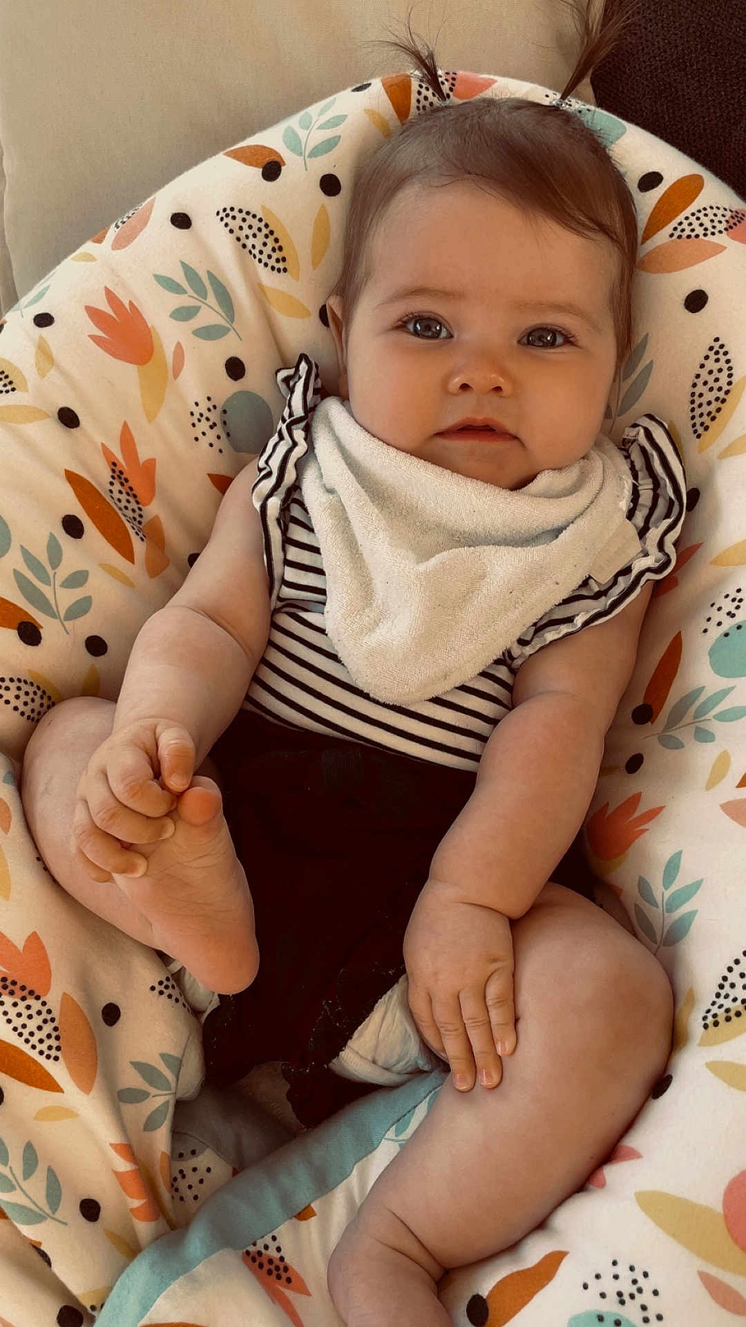 Léna a rejoint le concours — aidez-le/la à gagner de superbes lots ! baby, infant, child, cute, pigtails, striped_clothing, bib, foot, hand, cushion, floral_pattern, comfortable, indoors, skin, portrait, sitting, soft_toys, adorable, expression, relaxed