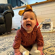 Mia joined the competition — help win amazing prizes! baby, child, smiling, sitting, carpet, indoor, clothing, bow, sock, happy, face, person, home, furniture, toy, floor, cute, infant, portrait, cozy