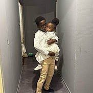 Nelya a rejoint le concours — aidez-le/la à gagner de superbes lots ! child, siblings, hallway, indoor, holding, affection, family, love, clothing, white_shirt, pants, socks, balloons, gray_wall, floor, portrait, people, toddler, boy, girl