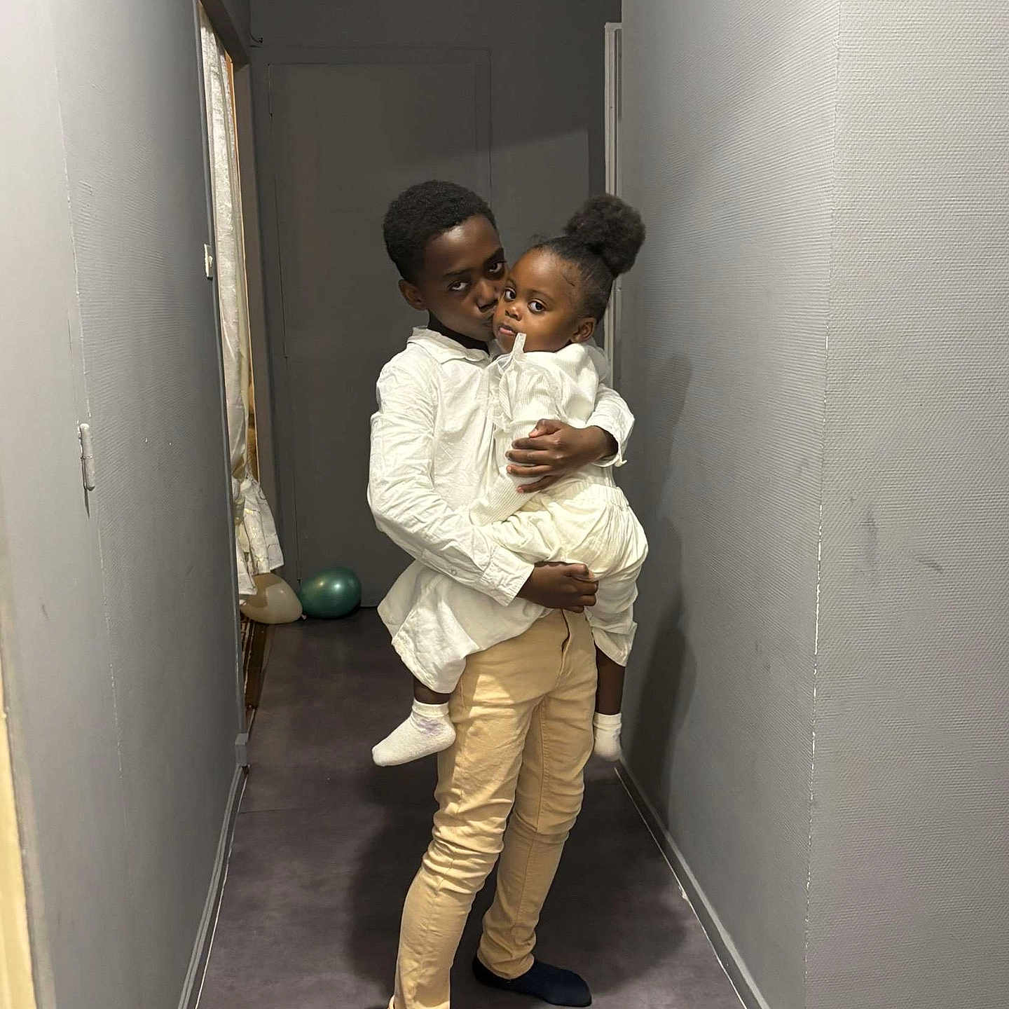 Nelya a rejoint le concours — aidez-le/la à gagner de superbes lots ! affection, balloons, boy, child, clothing, family, floor, girl, gray_wall, hallway, holding, indoor, love, pants, people, portrait, siblings, socks, toddler, white_shirt