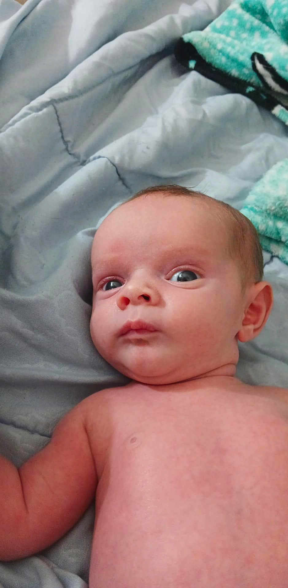 Emerson joined the competition — help win amazing prizes! baby, infant, face, eyes, skin, blanket, bed, lying_down, expression, curious, child, person, indoors, soft, comfort, newborn, head, shoulder, torso, young