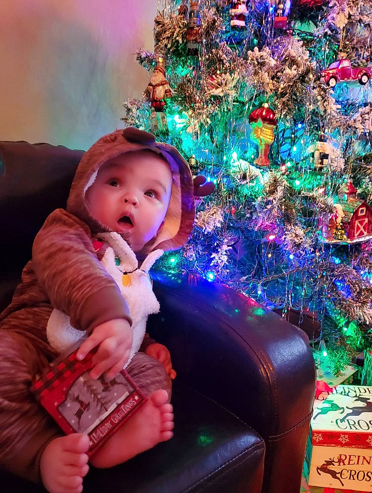 Archer is registered to the contest to win money with this photo: baby_toddler_clothing, beauty, blue, christmas, christmas_decoration, christmas_ornament, christmas_tree, comfort, fun, happy, headwear, holiday, holiday_ornament, lap, magenta, ornament, person, pink, purple, snapshot