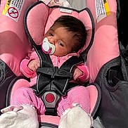Lydia is registered to the contest to win money with this photo: baby, infant, car_seat, safety_harness, pacifier, pink_clothing, striped_outfit, socks, blanket, bow, portrait, face, sleeping, sitting, vehicle, automotive, child, indoor, close_up, baby_gear