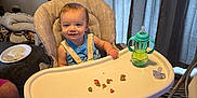 Myles joined the competition — help win amazing prizes! baby, high_chair, smiling, food, sippy_cup, pacifier, indoor, curtains, carpet, person, child, furniture, dog, plate, shoe, floor, table, feeding, happy, blue_clothing