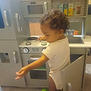 Charlie joined the competition — help win amazing prizes! appliance, cabinets, carpet, child, child_playing, curiosity, curly_hair, home, indoor, knobs, open_door, oven, plastic_toys, playset, sink, stove, toddler, toy_kitchen, white_onesie, young_child