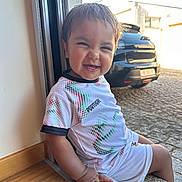 Kaïss a rejoint le concours — aidez-le/la à gagner de superbes lots ! child, toddler, smiling, sitting, doorway, window, shirt, shorts, hand, car, outdoor, pavement, sunlight, happy, face, clothing, person, casual, daylight, home