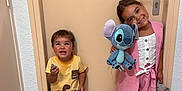 Lahïna a rejoint le concours — aidez-le/la à gagner de superbes lots ! child, children, door, floor, tile_floor, plush_toy, stuffed_animal, yellow_shirt, pink_shorts, pink_jacket, sandals, smiling, standing, indoor, toy, happy, person, brown_hair, cute, playful