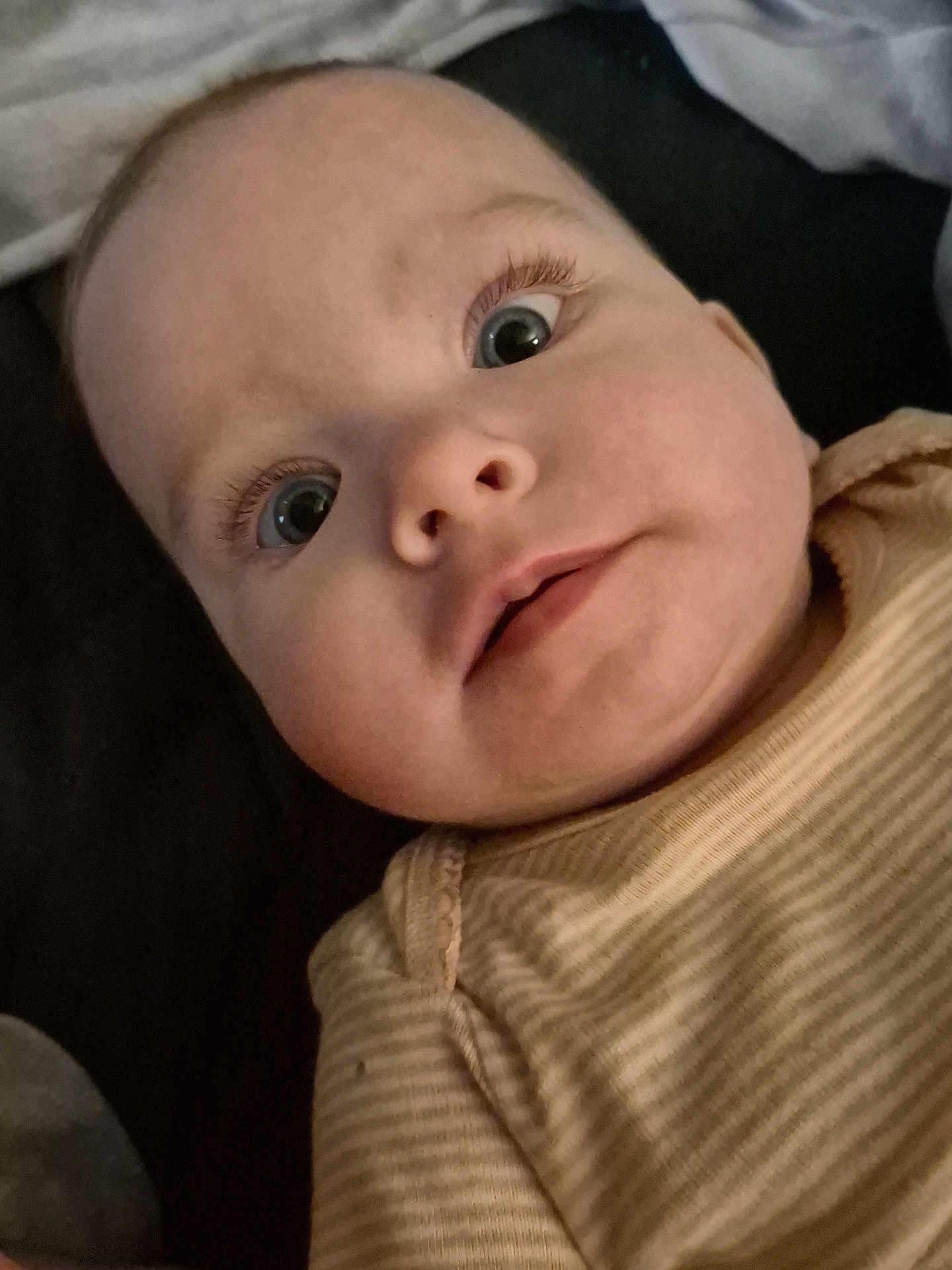 Ivy is registered to the contest to win money with this photo: baby, close_up, face, eyes, infant, child, portrait, expression, cute, curious, skin, person, clothing, striped, laying_down, long_eyelashes, soft_lighting, indoors, head, young