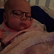 Zanayah is registered to the contest to win money with this photo: baby, sleeping, blanket, crib, face, glasses, cozy, infant, child, bed, soft, warm, indoor, person, portrait, cute, resting, peaceful, wrapped, toddler