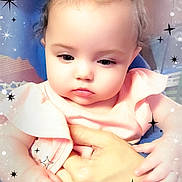 Kynlynn is registered to the contest to win money with this photo: baby, infant, child, portrait, close_up, pink_clothing, hands, being_held, sparkles_overlay, stars_overlay, soft_lighting, indoor, cute, round_cheeks, hair_bun, expression_serious, filter_effect, sitting, face, eyes